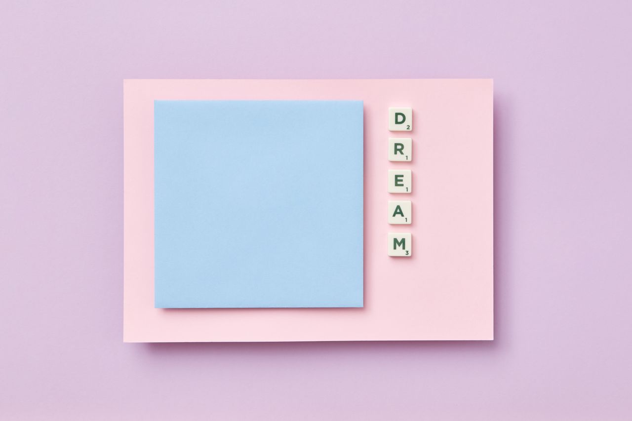 Flat lay of Scrabble tiles spelling dream on pastel surroundings with copy space.