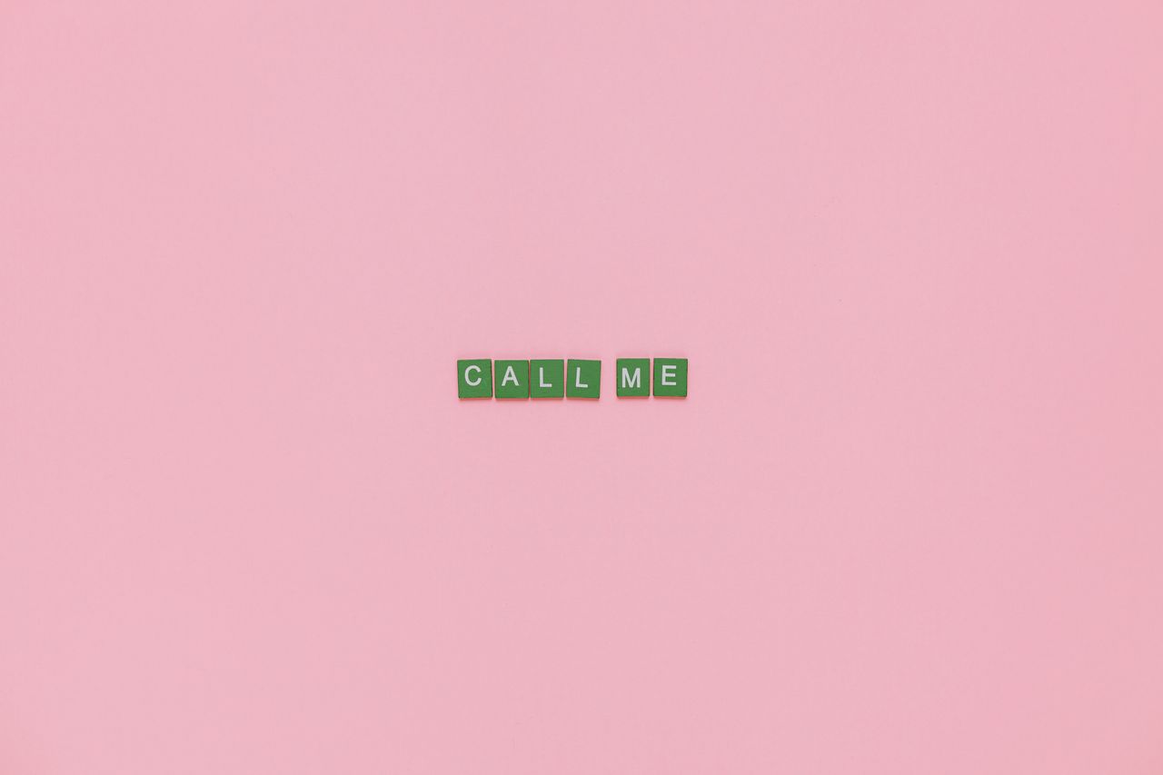 Scrabble letters forming CALL ME on a pink background, offering creative copyspace.